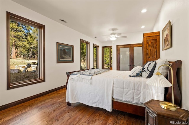 bedroom with multiple windows, ceiling fan, french doors, and dark wood-type flooring