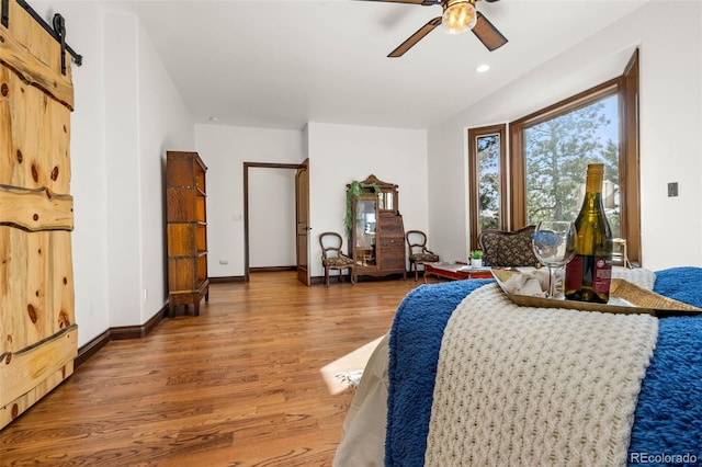 bedroom with hardwood / wood-style flooring, a barn door, and ceiling fan