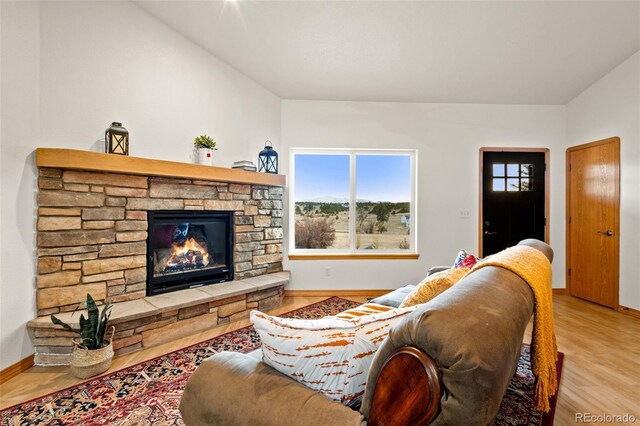 living room with a stone fireplace and light hardwood / wood-style flooring