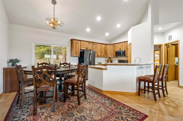 dining space featuring high vaulted ceiling, sink, and light hardwood / wood-style flooring