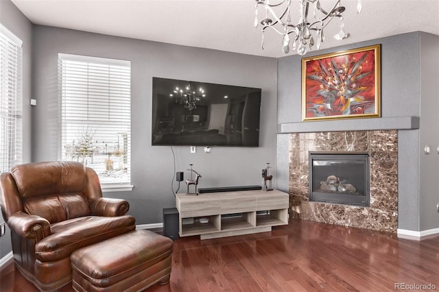 living area featuring a fireplace, plenty of natural light, a notable chandelier, and hardwood / wood-style flooring