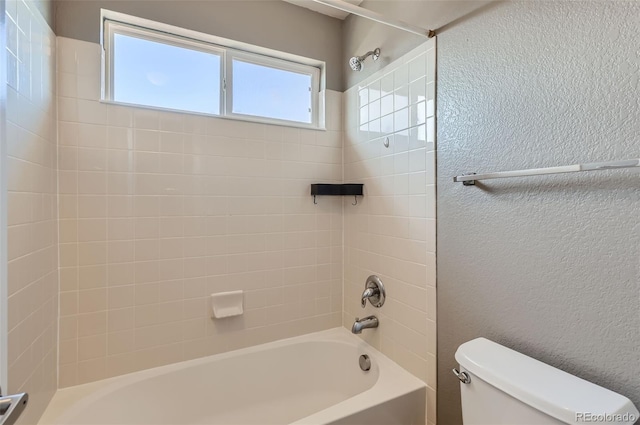 bathroom with toilet and tiled shower / bath