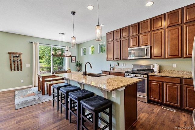 3115 Bryce Dr, Fort Collins, CO 80525 - kitchen with appliances with stainless steel finishes, dark wood-style flooring, a kitchen island with sink, light stone countertops, and recessed lighting