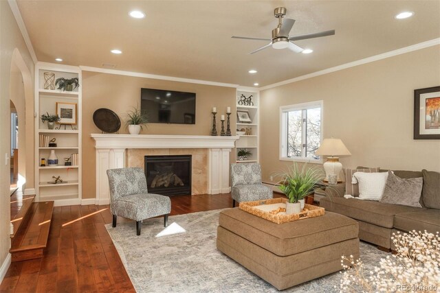 living room featuring ornamental molding, dark wood-type flooring, built in features, and a high end fireplace