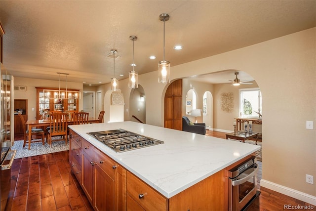 kitchen featuring pendant lighting, stainless steel appliances, a textured ceiling, a kitchen island, and dark hardwood / wood-style flooring