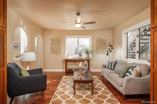 living room with ceiling fan, dark wood-type flooring, and a textured ceiling