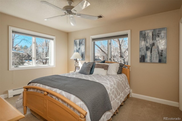 bedroom featuring light carpet, a baseboard heating unit, multiple windows, and a textured ceiling