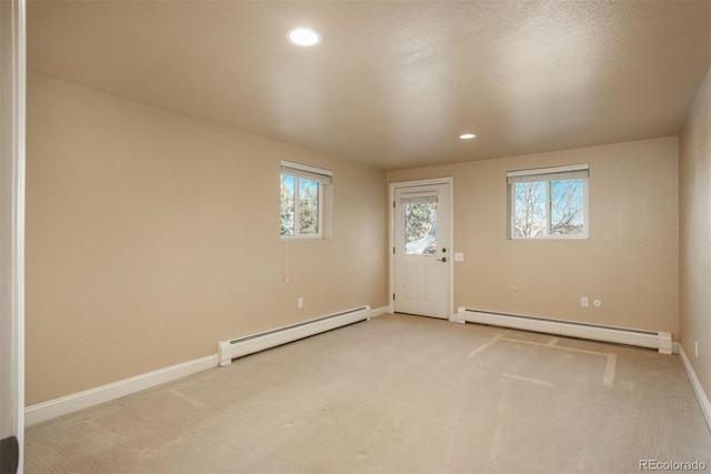 carpeted empty room with a healthy amount of sunlight and a baseboard heating unit