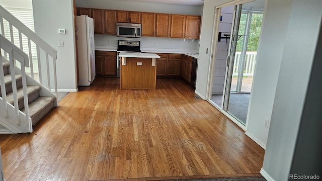 kitchen with light wood finished floors, stainless steel appliances, a kitchen island, and brown cabinets