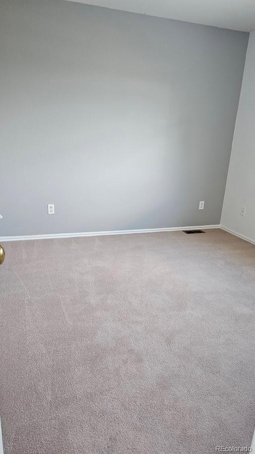 carpeted empty room featuring visible vents and baseboards