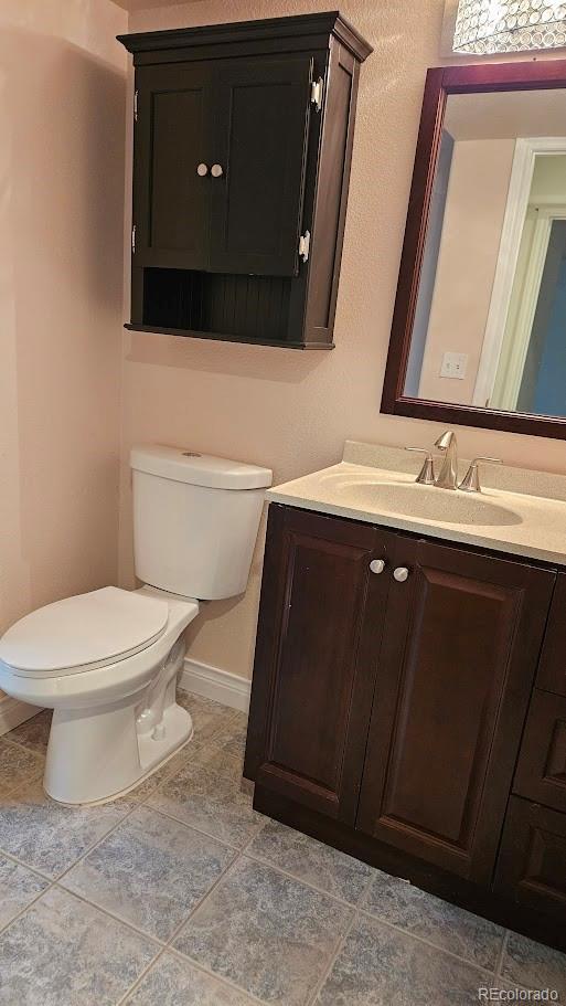 bathroom with toilet, vanity, and baseboards
