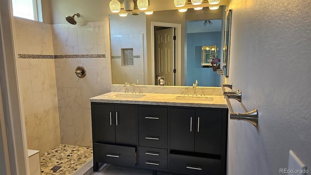 bathroom with double vanity, tiled shower, and a sink