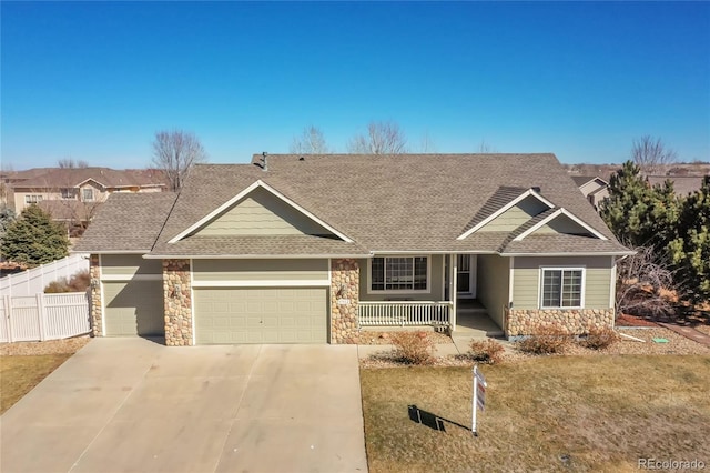 view of front of property with a porch, an attached garage, fence, driveway, and stone siding