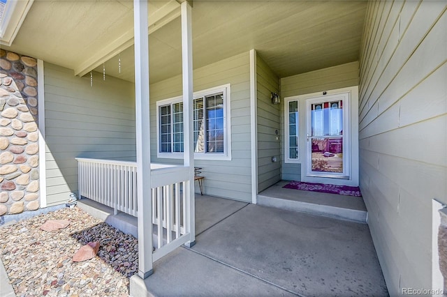 view of exterior entry with stone siding and a porch