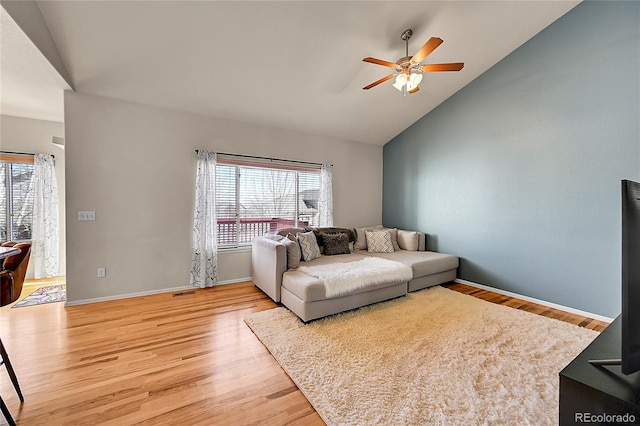 living area with baseboards, light wood finished floors, a ceiling fan, and a healthy amount of sunlight