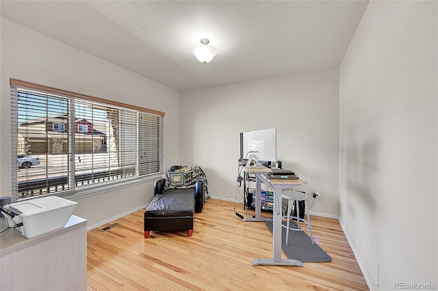 office space featuring baseboards, visible vents, and wood finished floors