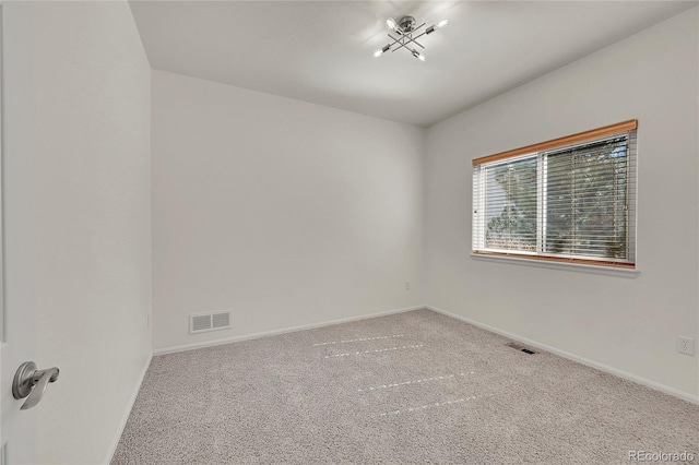 carpeted empty room featuring baseboards and visible vents