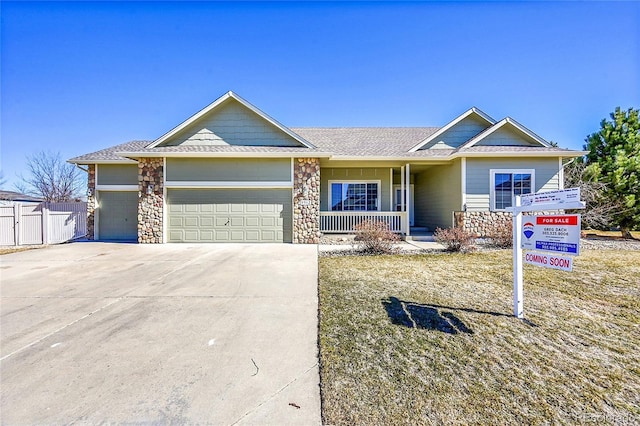 ranch-style house with a porch, concrete driveway, stone siding, and an attached garage