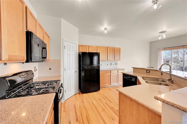 kitchen featuring a sink, light brown cabinetry, light wood-type flooring, black appliances, and tasteful backsplash