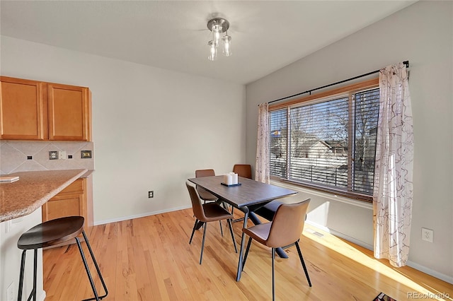 dining area with light wood finished floors, visible vents, and baseboards