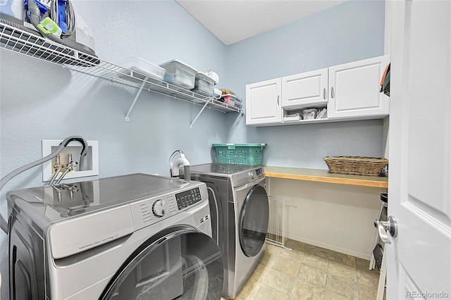 washroom featuring cabinet space, baseboards, and washer and clothes dryer