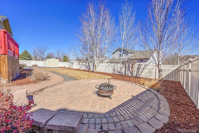 view of patio featuring a fire pit, an outdoor structure, and a fenced backyard