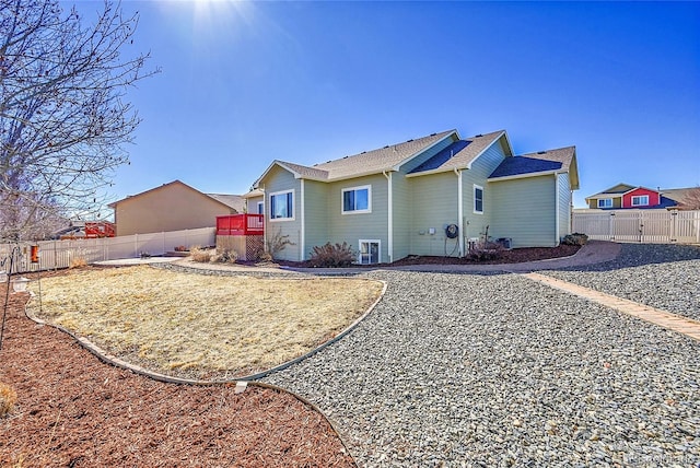 rear view of house featuring a fenced backyard and a gate