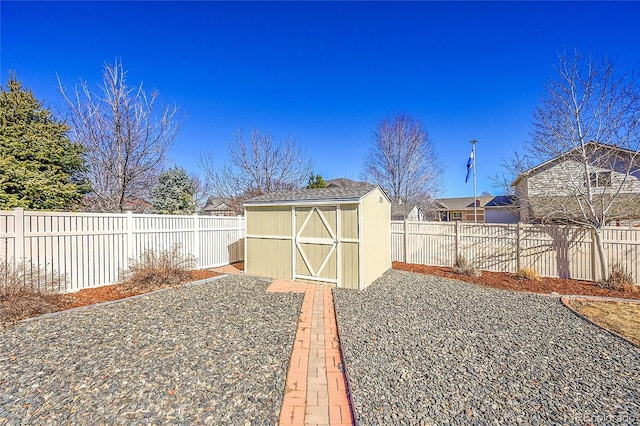 view of yard with a fenced backyard, a storage unit, and an outbuilding