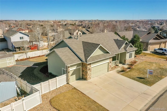 view of front of home featuring an attached garage, a fenced backyard, a residential view, and concrete driveway