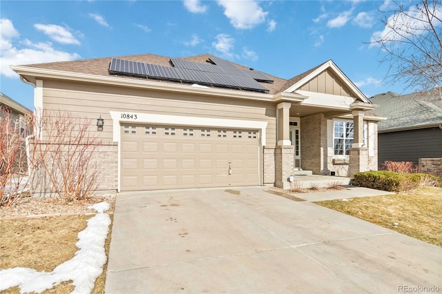 craftsman-style home with brick siding, solar panels, covered porch, concrete driveway, and an attached garage