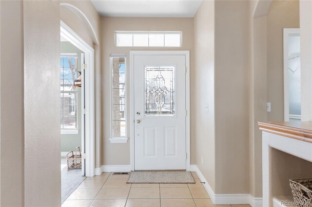 foyer entrance with light tile patterned floors, baseboards, visible vents, and a healthy amount of sunlight