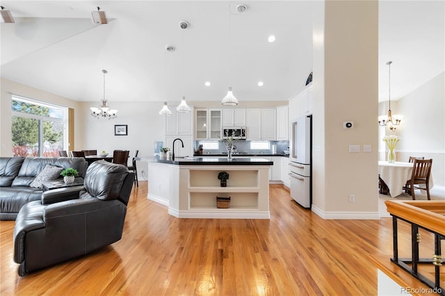 living room featuring lofted ceiling, a notable chandelier, light wood-style flooring, and baseboards