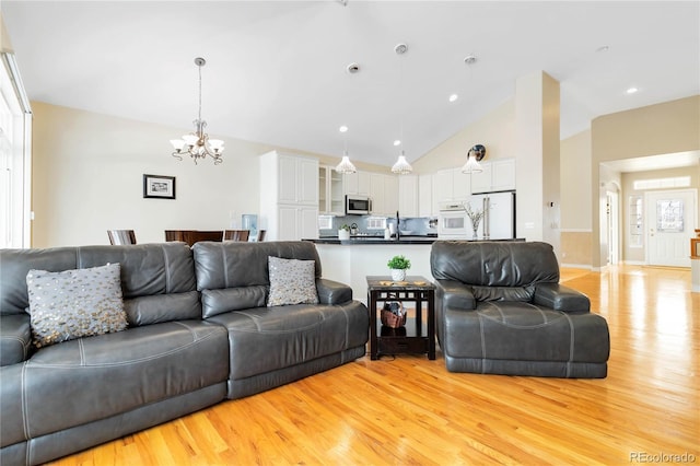 living room with light wood finished floors, high vaulted ceiling, and a notable chandelier