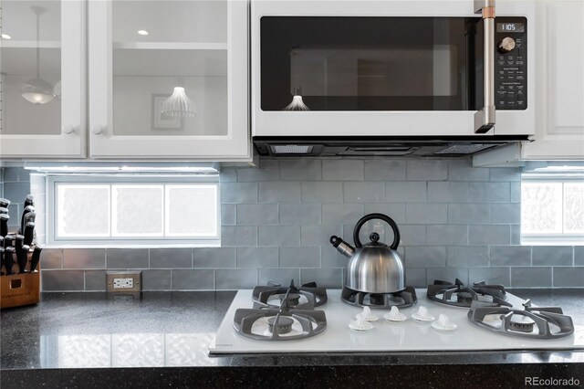 details featuring glass insert cabinets, white appliances, white cabinets, and backsplash