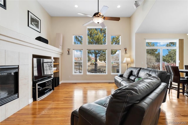 living area featuring baseboards, visible vents, a ceiling fan, light wood-type flooring, and a fireplace