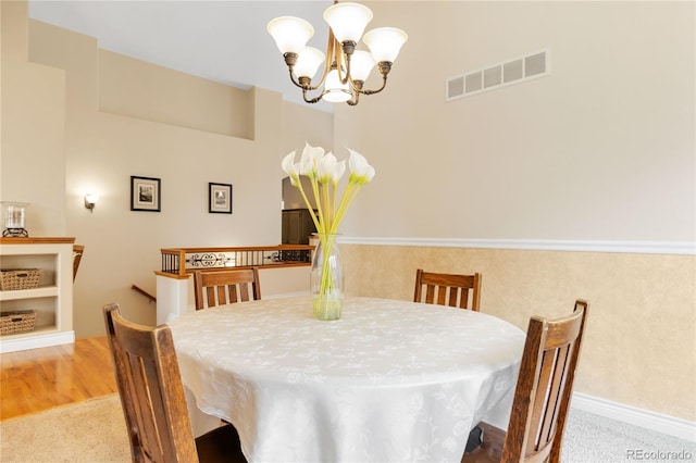 dining room with light wood finished floors, visible vents, and an inviting chandelier