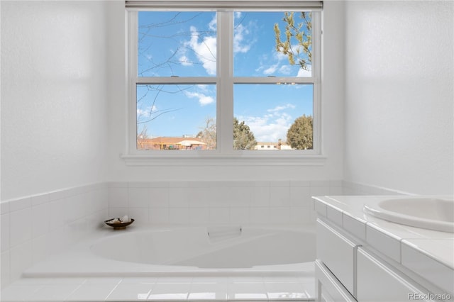 bathroom featuring a relaxing tiled tub and vanity