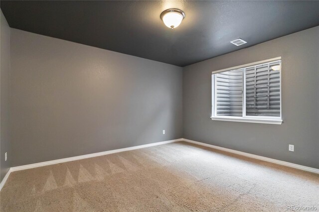 carpeted empty room featuring visible vents and baseboards