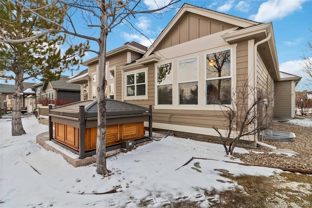 view of snowy exterior with board and batten siding and a garage