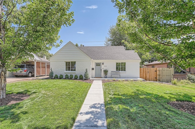 single story home with covered porch, roof with shingles, fence, and a front yard