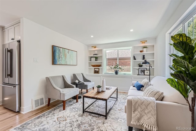 living room with built in features, recessed lighting, visible vents, light wood-style flooring, and baseboards