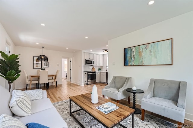 living area with light wood-style floors, baseboards, and recessed lighting