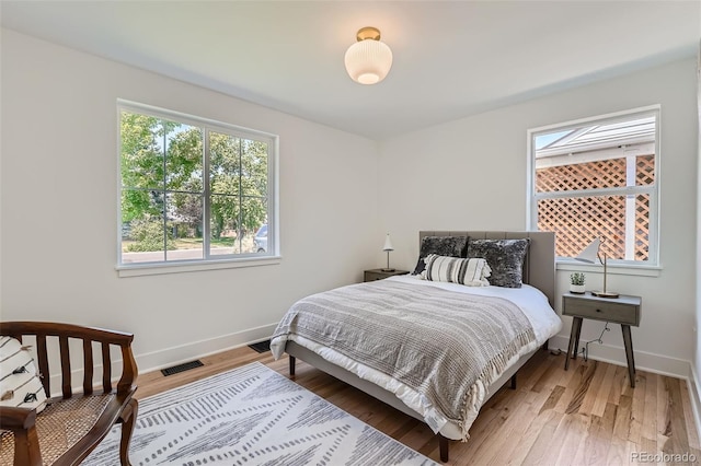 bedroom with wood finished floors, visible vents, and baseboards