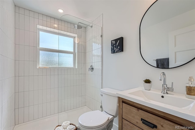 full bathroom with a tile shower, vanity, and toilet