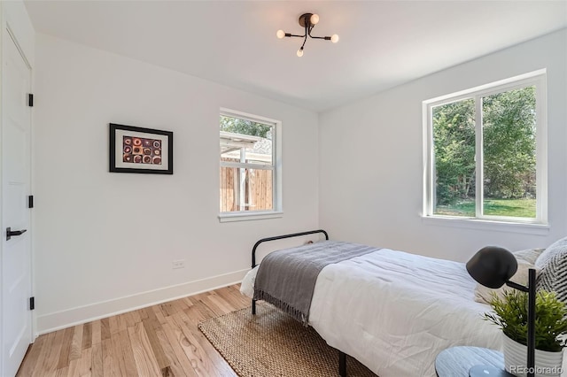 bedroom with light wood-style flooring, multiple windows, and baseboards