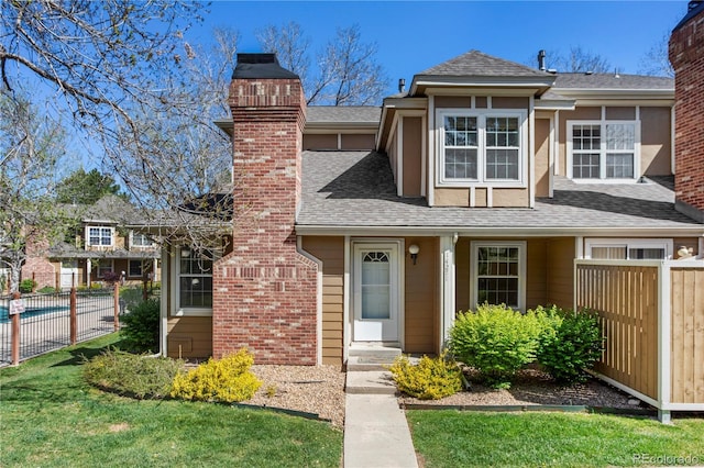 view of front of property with a shingled roof, fence, a front yard, and a chimney
