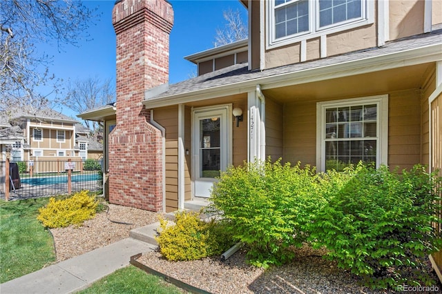 doorway to property with fence, a shingled roof, and a fenced in pool