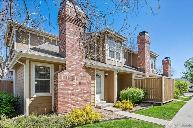 traditional home featuring fence, a chimney, and a shingled roof