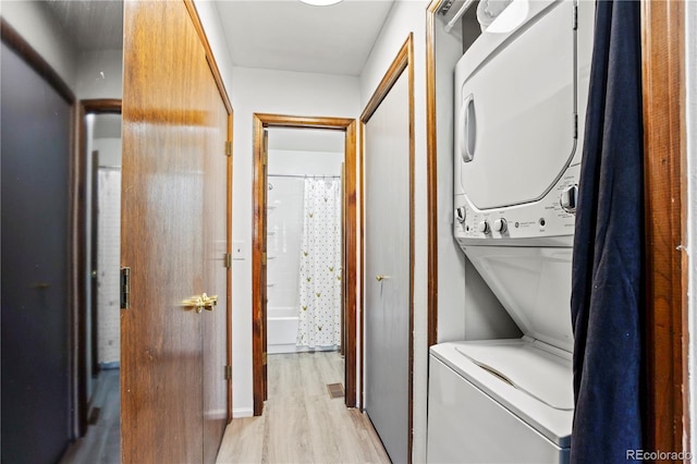 laundry room featuring laundry area, light wood-style flooring, and stacked washer / dryer