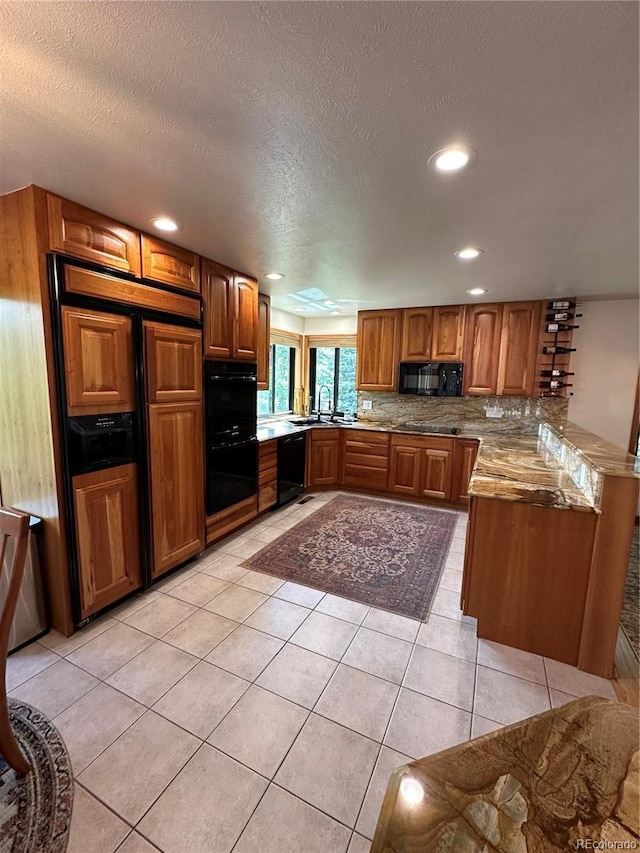 7454 Queen Cir, Arvada, CO 80005 - kitchen with black appliances, brown cabinets, a peninsula, recessed lighting, and light tile patterned flooring